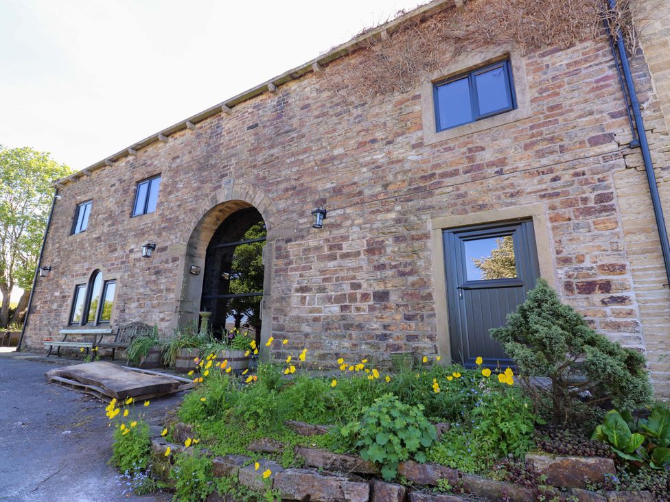 An outdoor view of a stone building with windows and flowers at Bib Knowl Farm in Littleborough