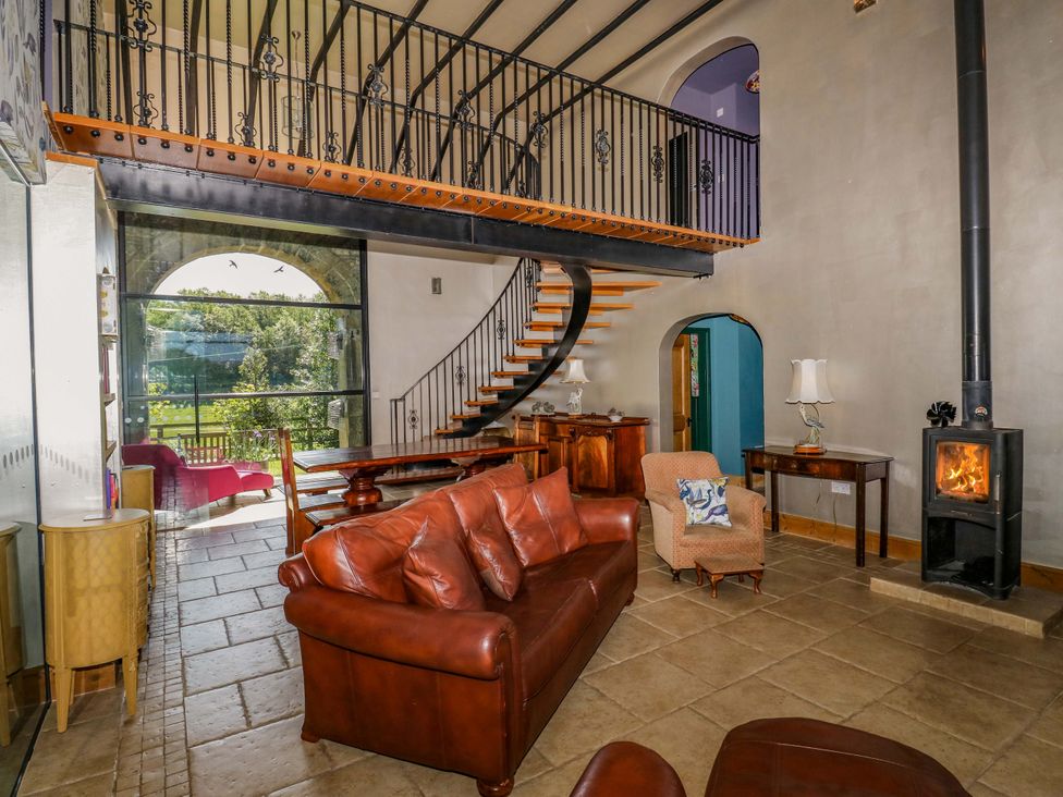 A living room with a staircase, sofa, and wood stove at Bib Knowl Farm in Littleborough