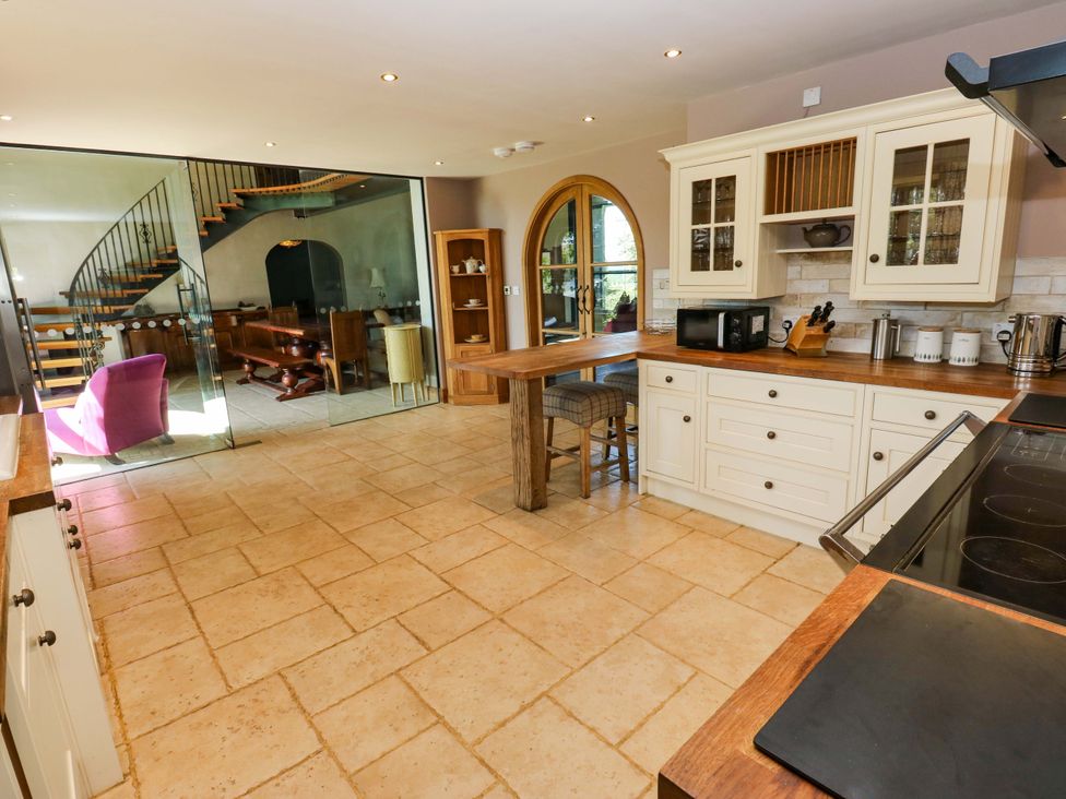 A kitchen with cabinets, bar stools, and a staircase at Bib Knowl Farm in Littleborough