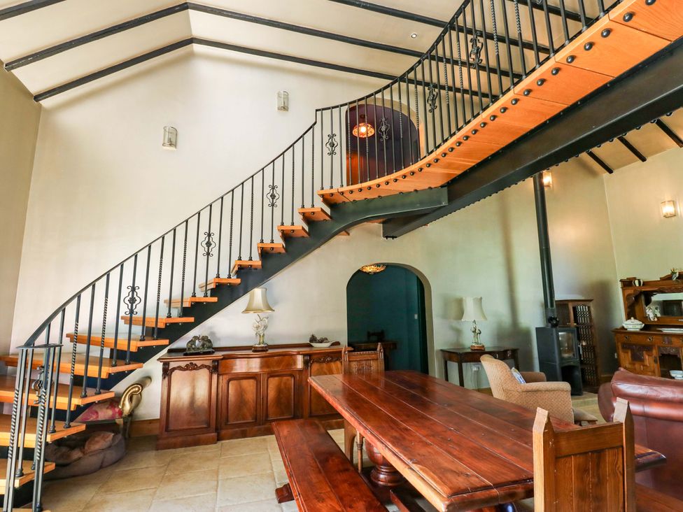 A dining room with a staircase and wooden table at Bib Knowl Farm in Littleborough