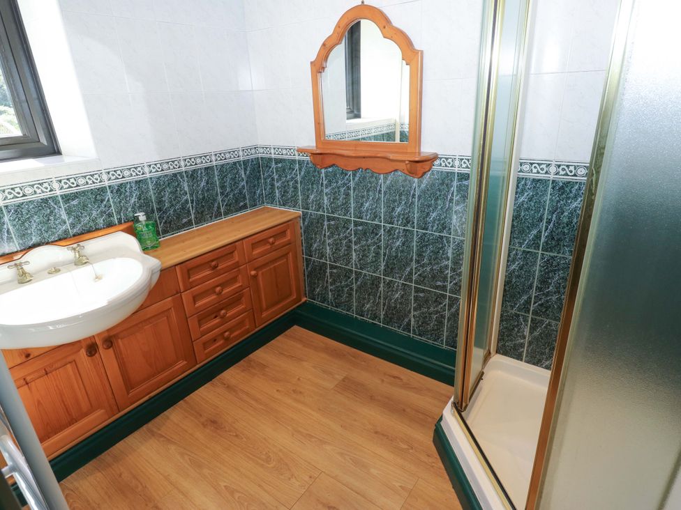 A bathroom with a sink, mirror, shower, and cabinet at Bib Knowl Farm in Littleborough
