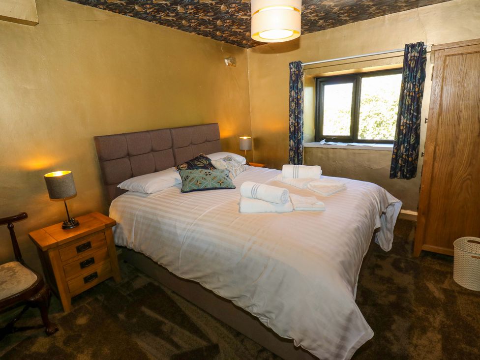 A bedroom with a bed and bedside table at Bib Knowl Farm in Littleborough