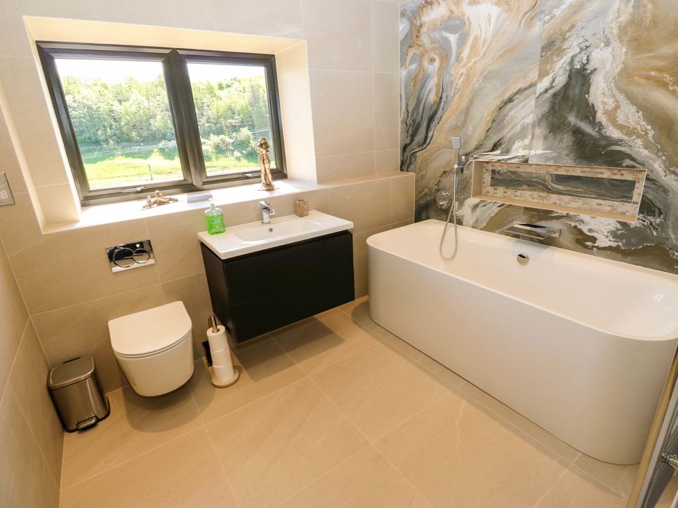 A bathroom with a bathtub, sink, and toilet at Bib Knowl Farm in Littleborough