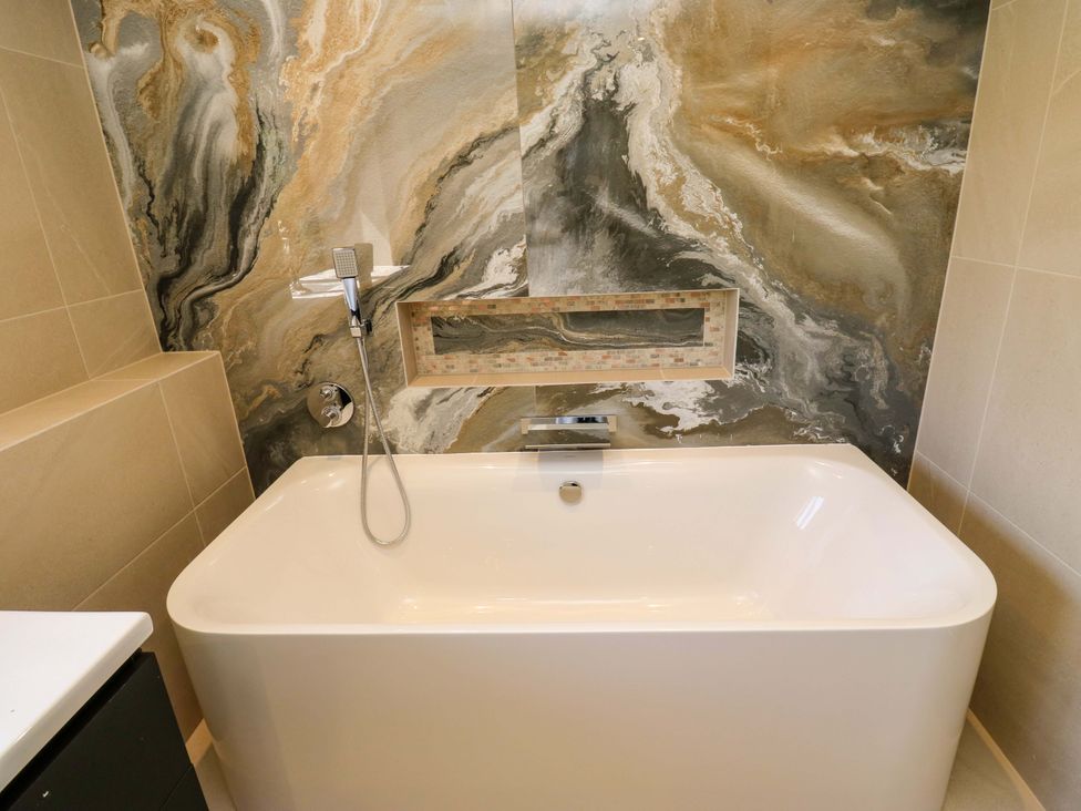 A bathroom with a bathtub and wall features at Bib Knowl Farm in Littleborough