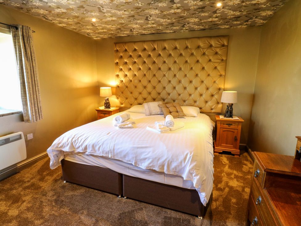 A bedroom with a bed, bedside tables, and lamps at Bib Knowl Farm in Littleborough