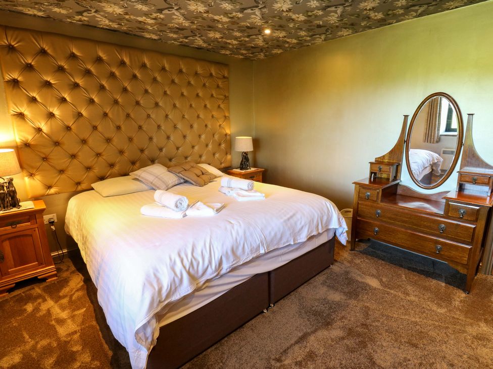 A bedroom with a large bed and dresser at Bib Knowl Farm Littleborough