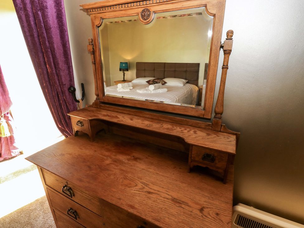 A dresser with a mirror and a bed in the background at Bib Knowl Farm Littleborough