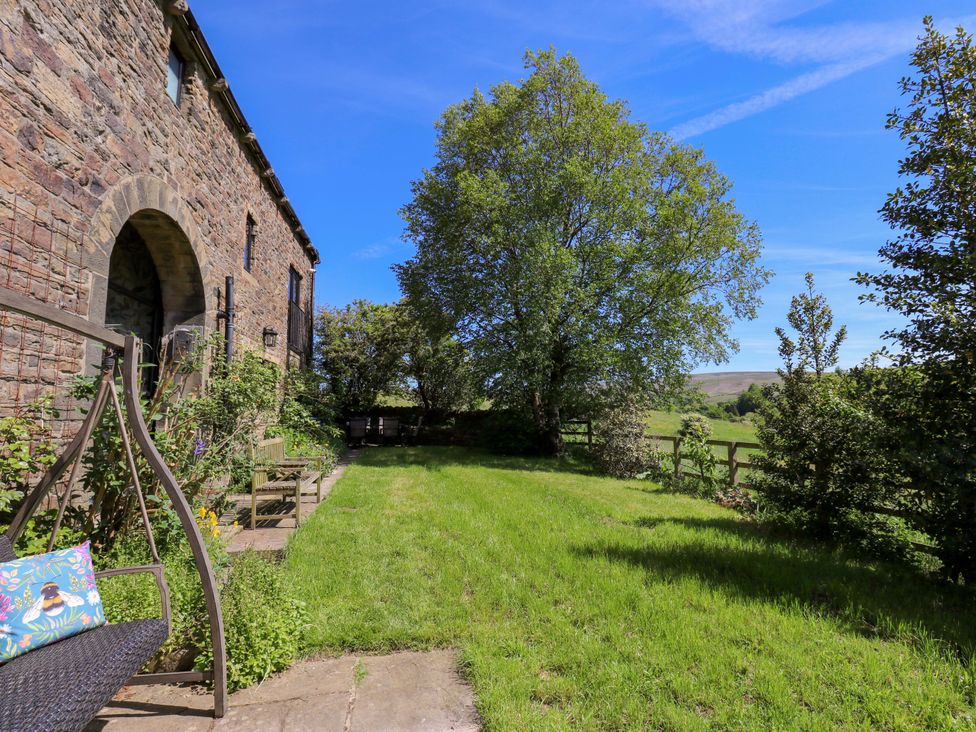 A garden with a stone building and trees at Bib Knowl Farm in Littleborough
