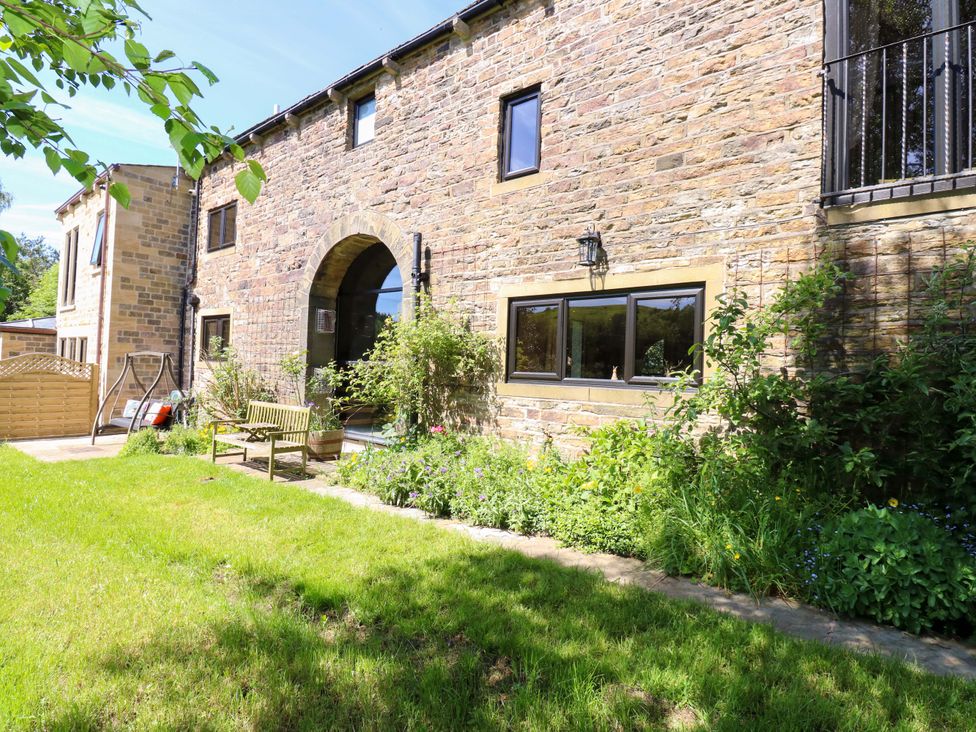 An outdoor area with a stone wall and bench at Bib Knowl Farm in Littleborough