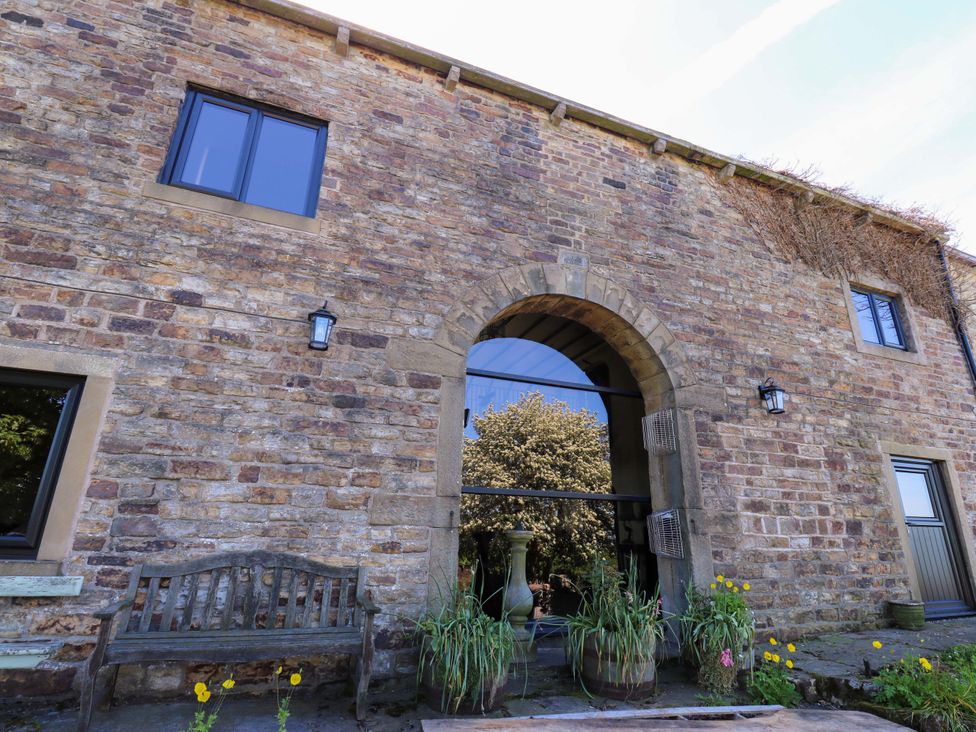 An exterior view of a stone building with a bench and plants at Bib Knowl Farm in Littleborough