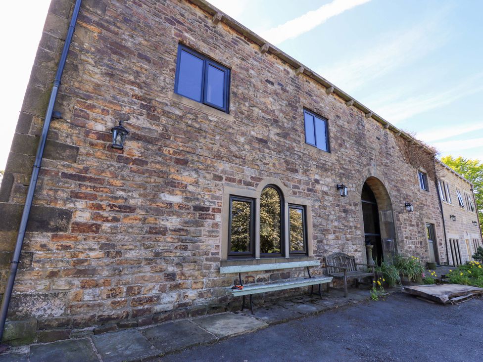 An exterior view of a stone building with windows and a bench at Bib Knowl Farm in Littleborough