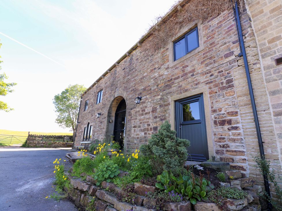 An exterior view of a stone building with windows and plants at Bib Knowl Farm Littleborough