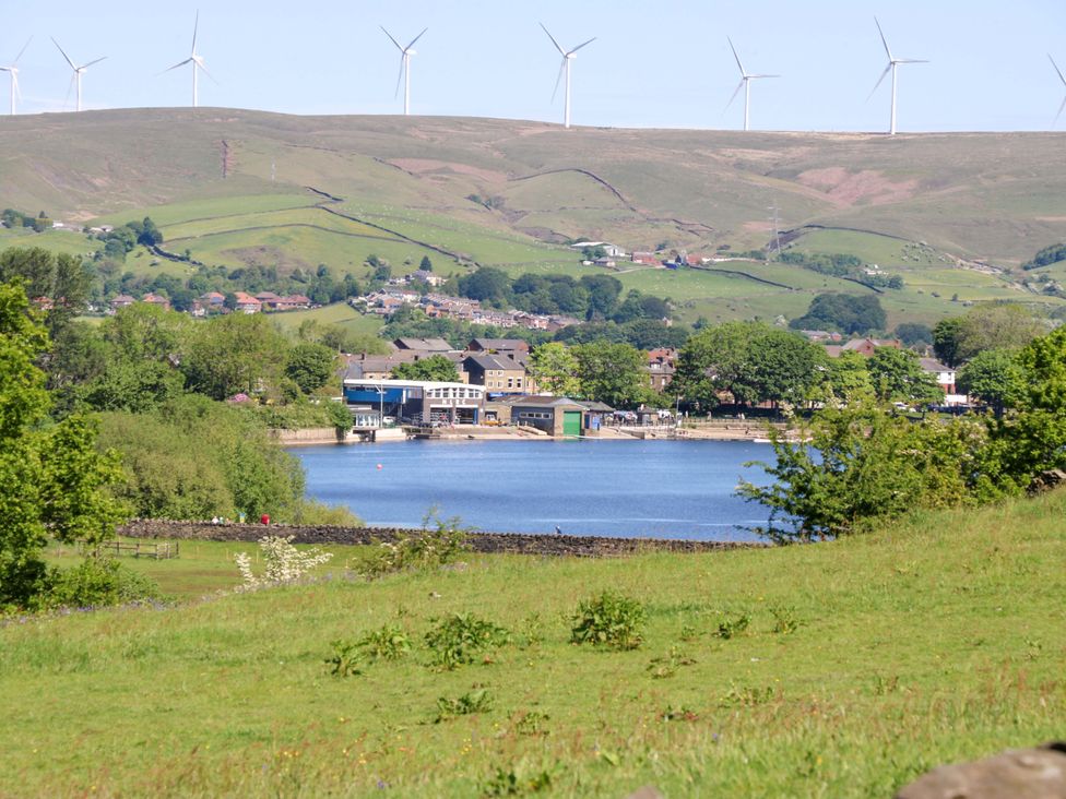 A view of a river with buildings and wind turbines at Bib Knowl Farm in Littleborough