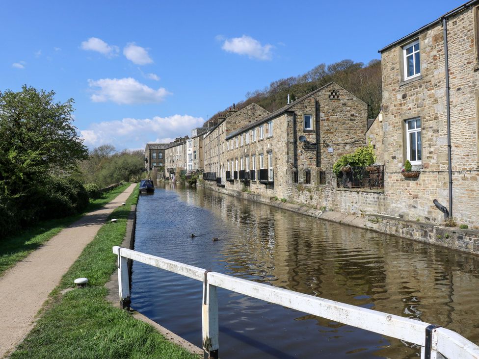 A canal with buildings alongside and a path at Bib Knowl Farm in Littleborough