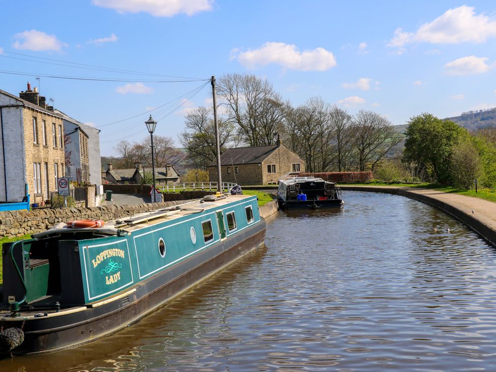 A canal with narrowboats and houses along the bank at Bib Knowl Farm in Littleborough