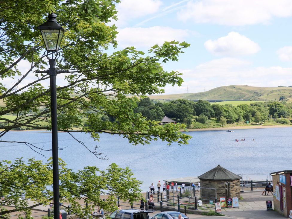 A view of a lake with a boat and people at Bib Knowl Farm in Littleborough