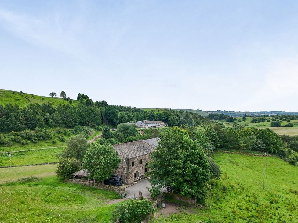 An outdoor view of a stone house and landscape at Bib Knowl Farm in Littleborough