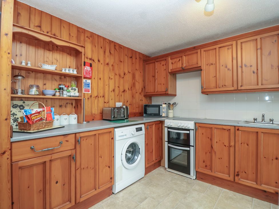 A kitchen with wooden cabinets and appliances at Manorcombe 1 Honicombe Park near Gunnislake