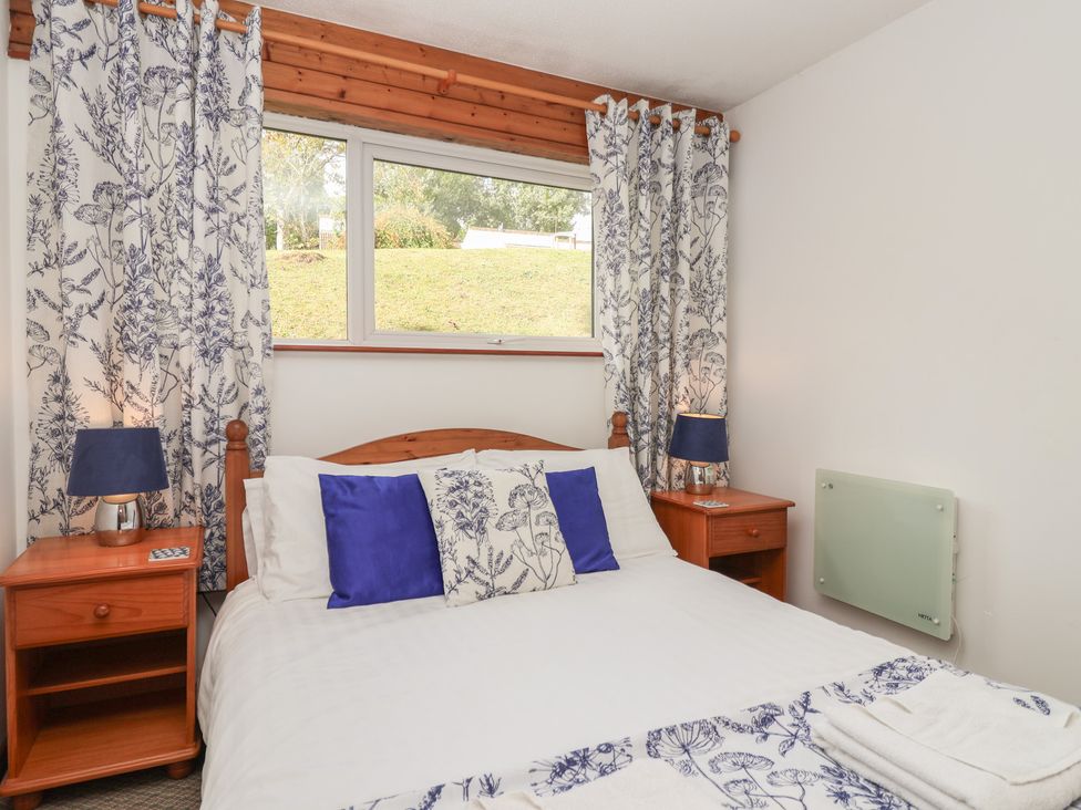 A bedroom with a bed and nightstands at Manorcombe 1 Honicombe Park near Gunnislake