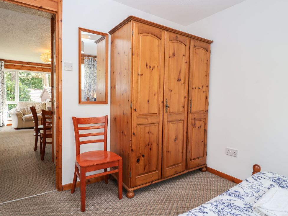 A bedroom with a wardrobe and a chair at Manorcombe 1 Honicombe Park near Gunnislake
