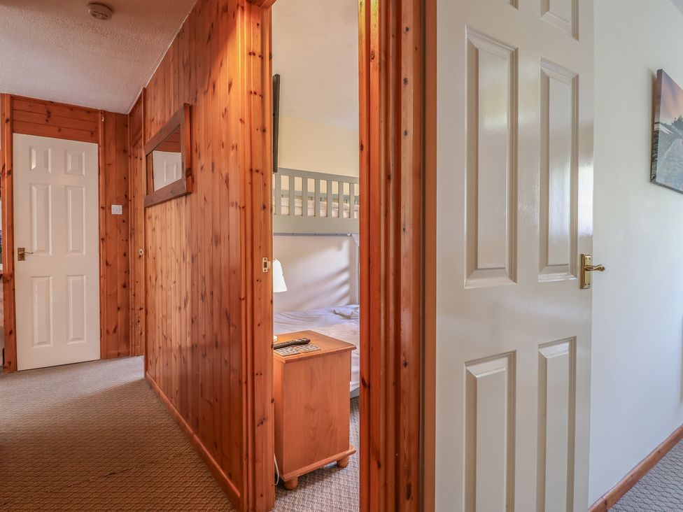 A hallway with doors and a glimpse of a bed at Manorcombe 1 in Honicombe Park near Gunnislake