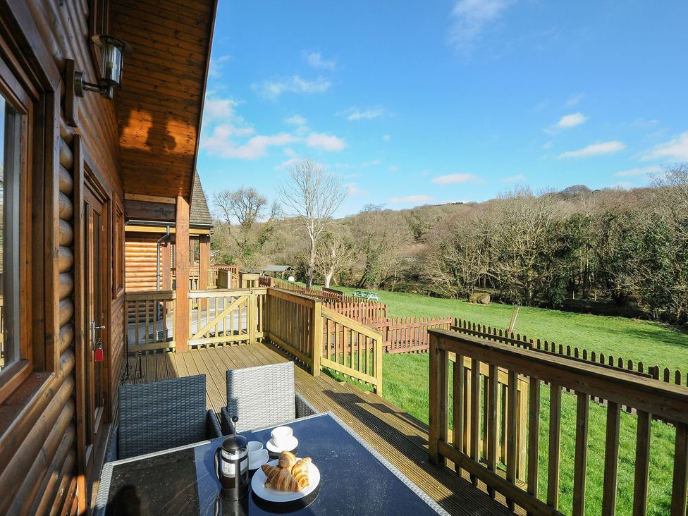An outdoor area with a table and chairs overlooking a field at Trevano in St Breward