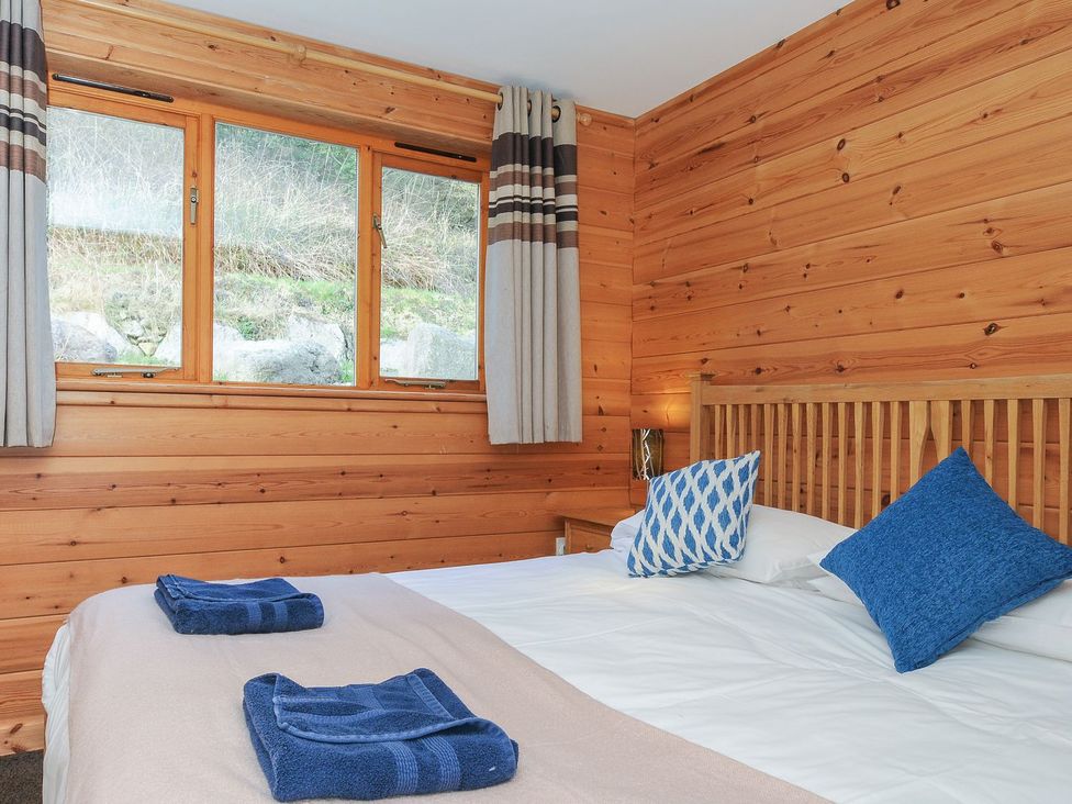 A bedroom with a bed, pillows, towels, and windows at Trevano in St Breward