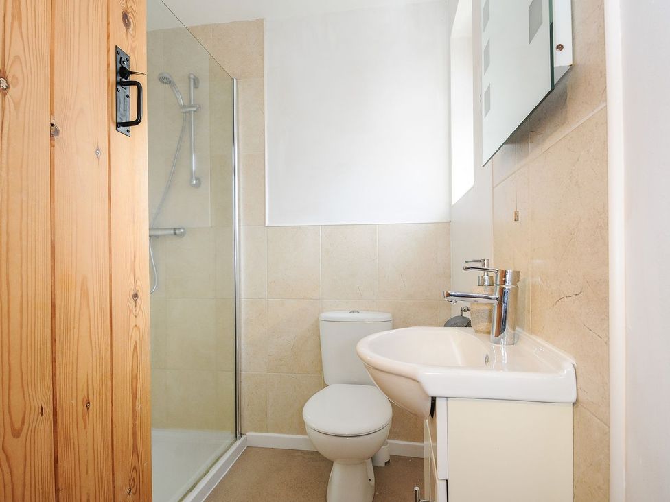 A bathroom with a shower, toilet, sink and mirror at Trevano in St Breward