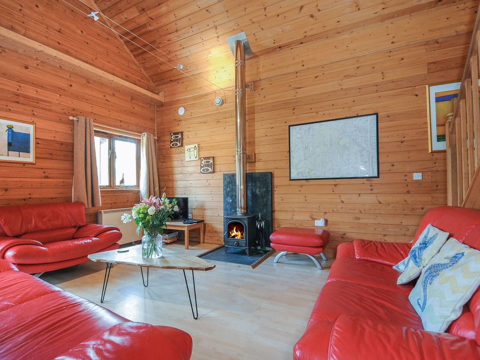A living room with a red sofa and fireplace at Pencarrow St Breward