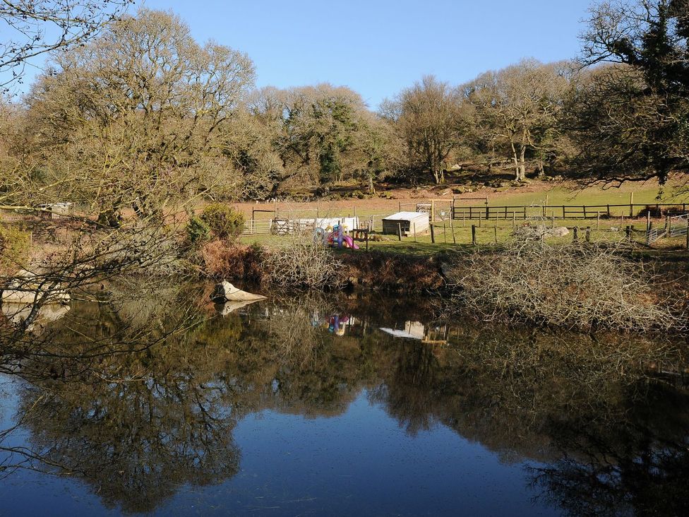 A pond with trees and a shed at Pencarrow in St Breward