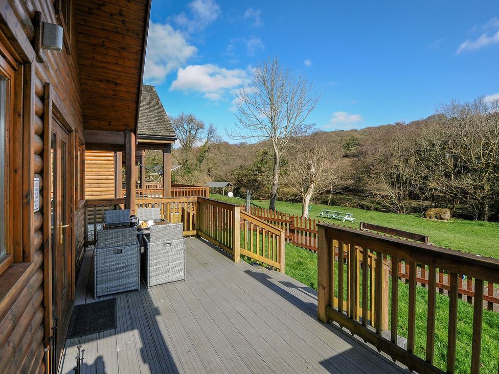 An outdoor area with a deck, table and chairs at Trebah in St Breward