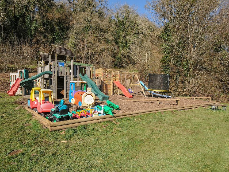 An outdoor play area with a playground and various toys at Eden in St Breward