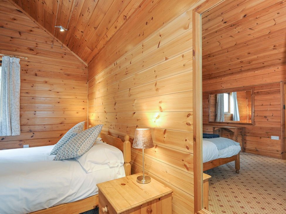 A bedroom with two beds and wooden walls at Heligan in St Breward