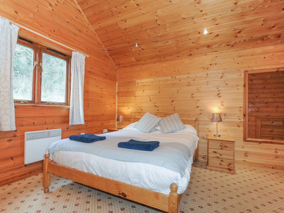 A bedroom with wooden walls and a large bed at Heligan in St Breward