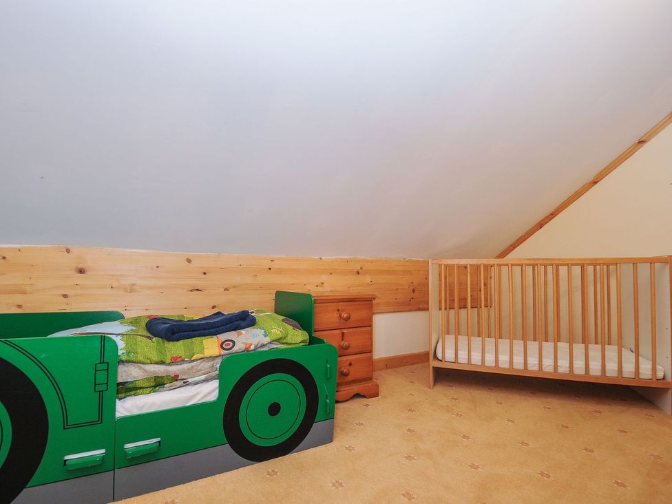 A children's bedroom with a car-shaped bed and a crib at Heligan St Breward