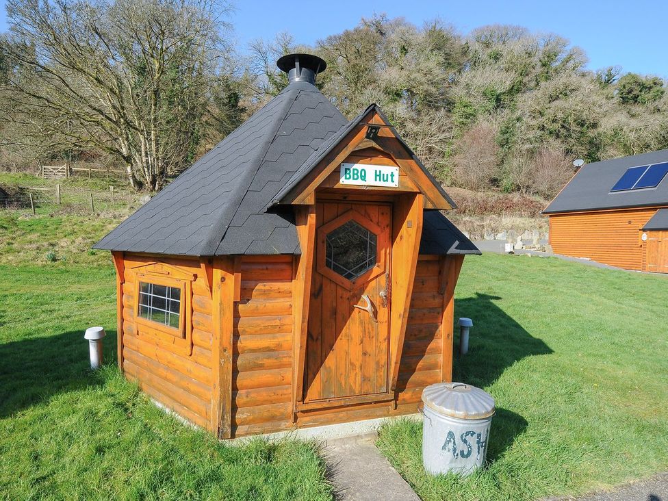 A BBQ hut with a door and window outside at Heligan in St Breward