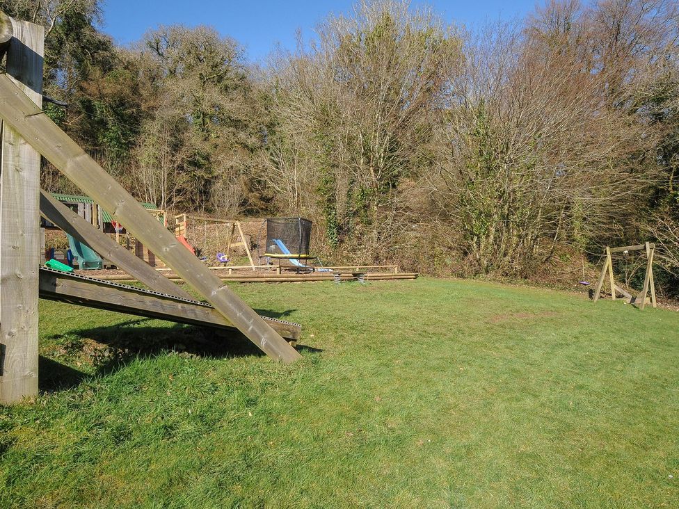 A playground with swings and a slide in an outdoor space at Heligan St Breward