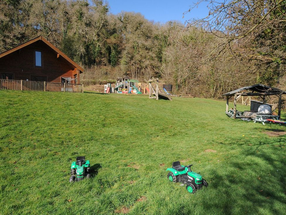 A garden with a wooden house and playground equipment at Heligan in St Breward