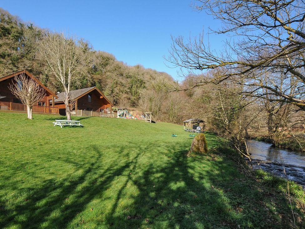 An outdoor area with cabins, picnic table, and playground at Heligan in St Breward