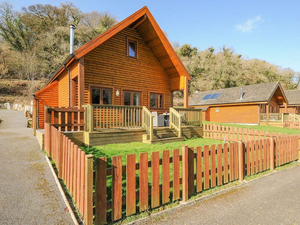 A wooden cabin with a deck and fence at Polzeath St Breward