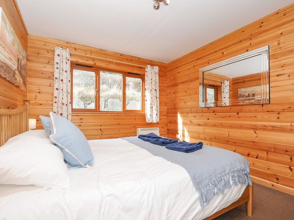 A bedroom with a bed and windows at Polzeath in St Breward