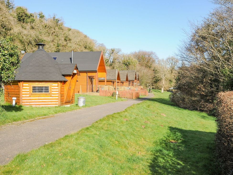 Log cabins and pathway surrounded by trees at Polzeath in St Breward