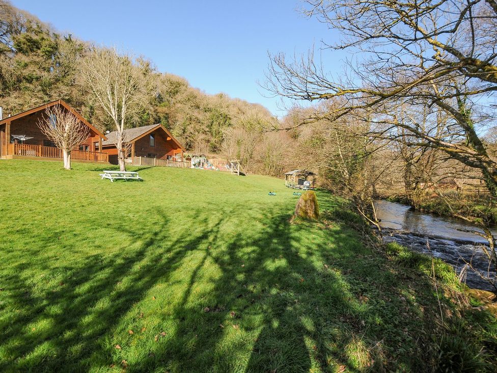 Two wooden cabins with a river and playground at Polzeath in St Breward