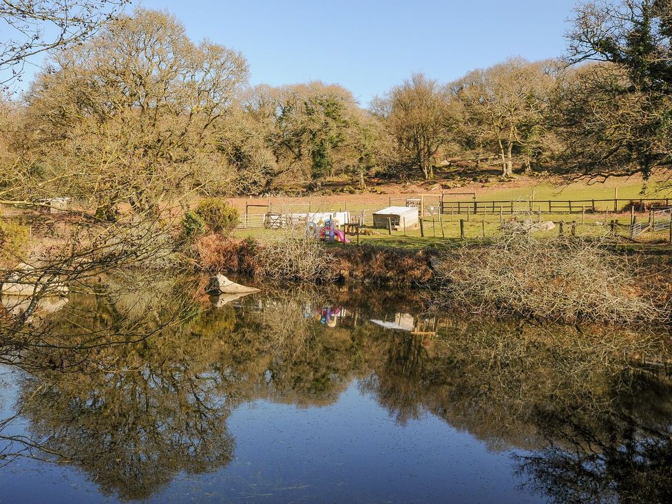 A view of a pond with trees and playground equipment at Polzeath in St Breward