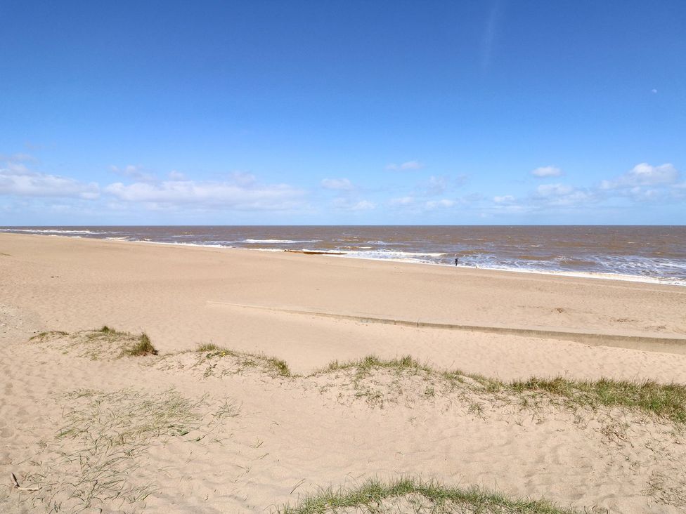 A beach with ocean waves and a person in the distance at 3 Cherry Blossom Skegness
