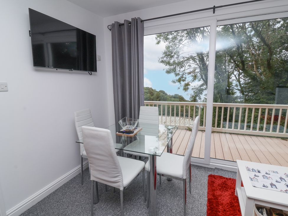 A dining room with a glass table and television at I C Lundy Too Bideford Bay Holiday Park near Woolfardisworthy