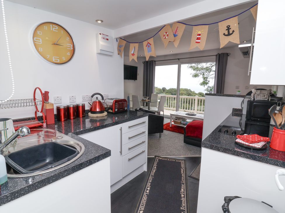 A kitchen with appliances and a living area at I C Lundy Too Bideford Bay Holiday Park near Woolfardisworthy