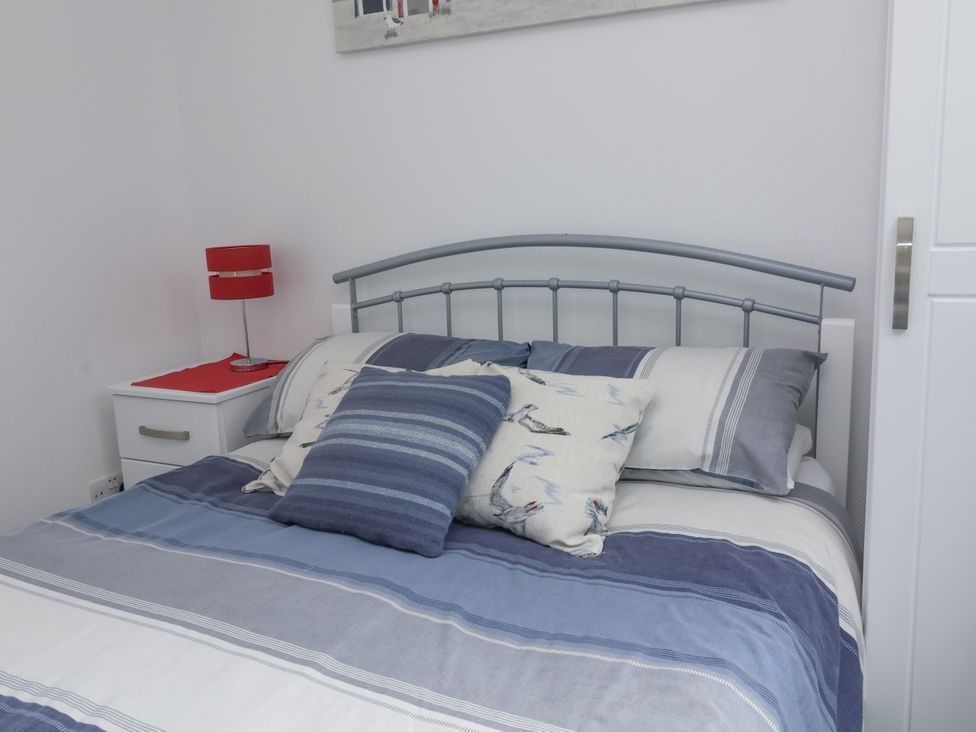 A bedroom with a bed and bedside table at I C Lundy Too Bideford Bay Holiday Park near Woolfardisworthy