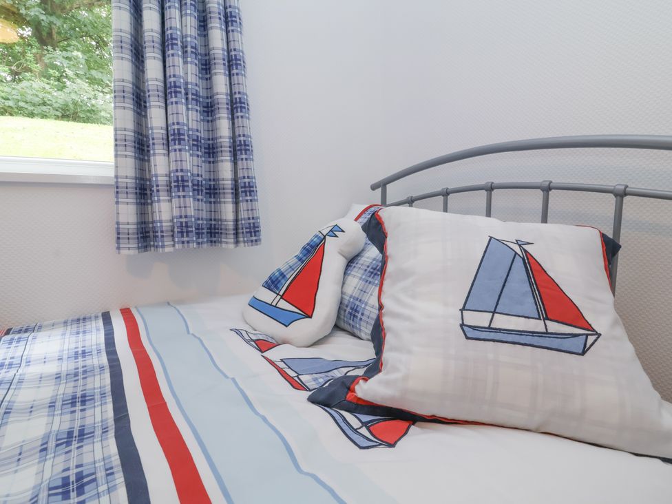 A bedroom with a bed and nautical themed pillows at I C Lundy Too Bideford Bay Holiday Park near Woolfardisworthy