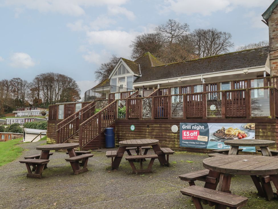 An outdoor area with wooden tables and a building at I C Lundy Too Bideford Bay Holiday Park near Woolfardisworthy